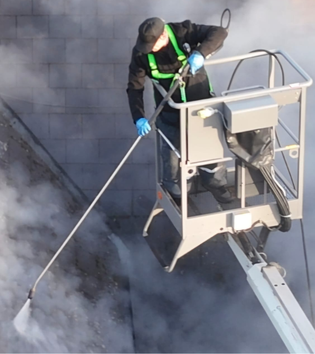 Professional pressure washer cleaning a paved driveway surface outdoors